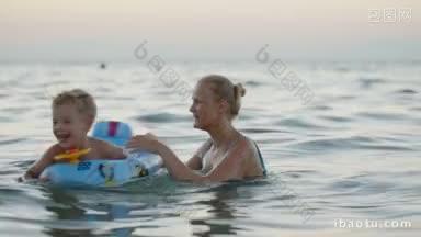 妈妈和小儿子在海里玩得很<strong>开心</strong>，女人在旋转，<strong>兴奋</strong>的男孩在橡胶圈里